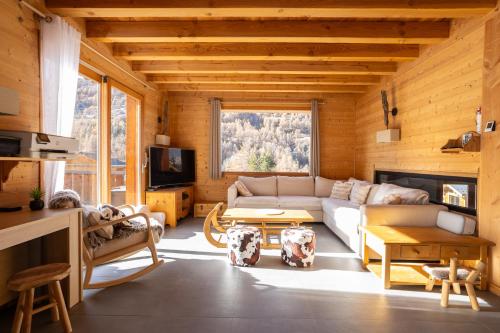 a living room with a couch and a table at Chalet La Tanière 14 Pers - piscine chauffée et sauna - Vars Saint Marcellin in Vars