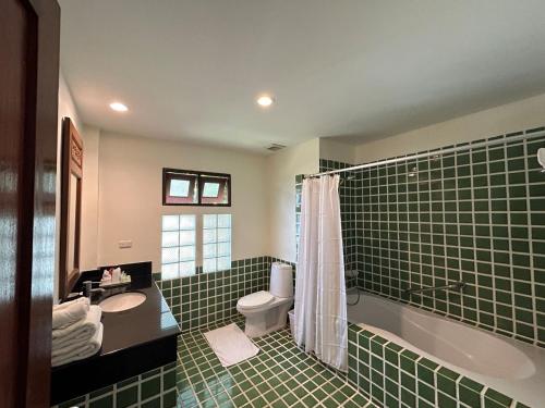 a bathroom with a sink and a tub and a toilet at Teak Garden Resort, Chiang Rai in Chiang Rai