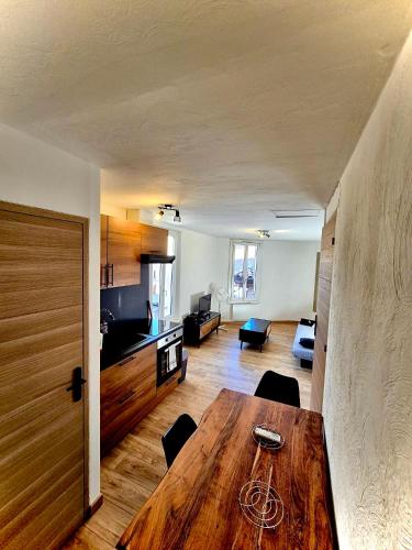 a room with a wooden table and a living room at Charmant appart climatisé in Draguignan