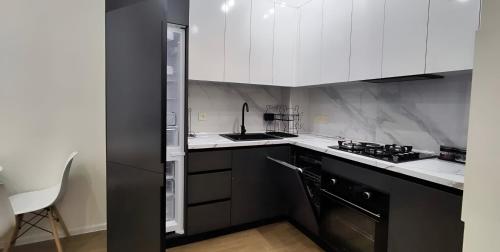 a kitchen with white cabinets and a black refrigerator at CozyNest Apartment In Yerevan, Center in Yerevan