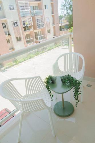 two white chairs and a table on a balcony at Lujoso departamento en Boca Chica in El Higo