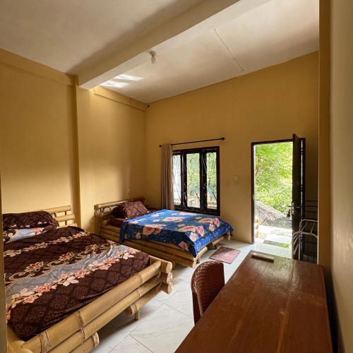 Un dormitorio con dos camas y una mesa y una ventana. en Sunrise Bukit Asam Home Stay, en Kuta Lombok