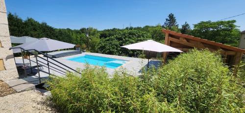 Una piscina con dos sombrillas al lado de una casa. en Villa Béa, en Filolie