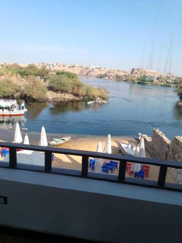 Una vista de un río con sillas y una playa. en Aki Nira Guest House & اكي نيرا بيتش, en Asuán
