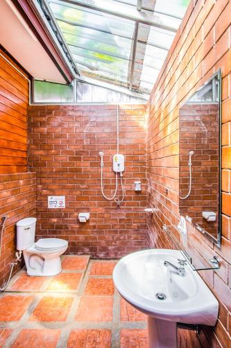 a brick bathroom with a toilet and a sink at Samran Resort in Chalong