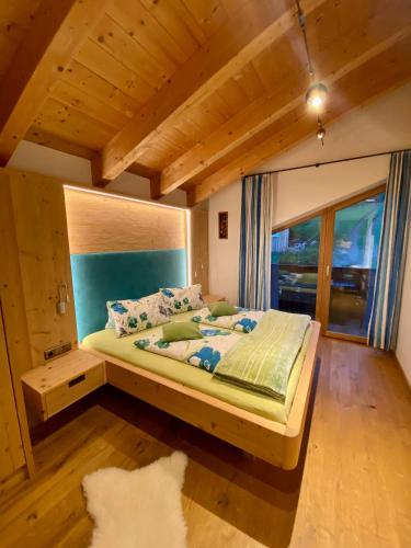 a bedroom with a large bed with a large window at Gasthaus Dorfberg in Kartitsch