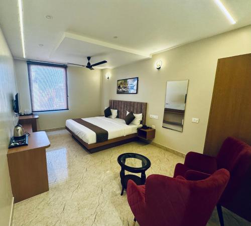 a hotel room with a bed and two chairs at The Rivanta Hotel Near Airport Road Mohali Zirakpur Chandigarh in Zirakpur