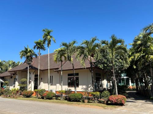 een huis met palmbomen ervoor bij Teak Garden Resort, Chiang Rai in Chiang Rai