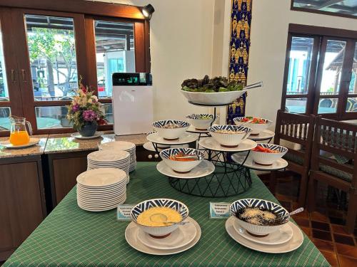 een tafel met borden en kommen met eten erop bij Teak Garden Resort, Chiang Rai in Chiang Rai