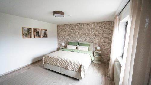 een slaapkamer met een bed en een bakstenen muur bij Apartment am Golfplatz in Mackenbach in Mackenbach