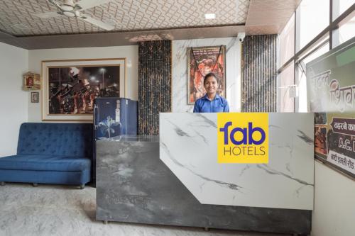 Un hombre está parado detrás de un cartel en un vestíbulo. en FabHotel Shivkashi Inn - Dasaswamedh Ghat, en Varanasi