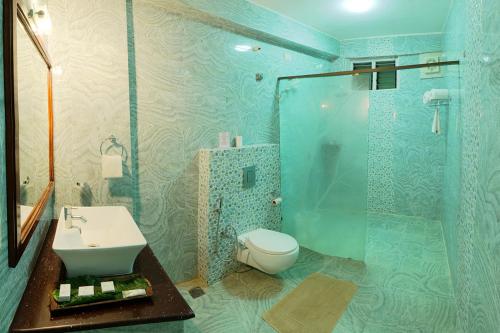 Un baño con inodoro, lavabo y ducha. en Gokulam Grand Resort & Spa, Coorg, en Kushālnagar