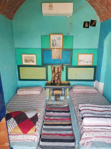 two beds in a small room with blue walls at Seheil Antique House in Jazīrat Salūjah