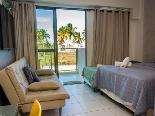 a bedroom with a bed and a couch and a window at Mana Beach Experience Muro Alto C219 in Porto De Galinhas