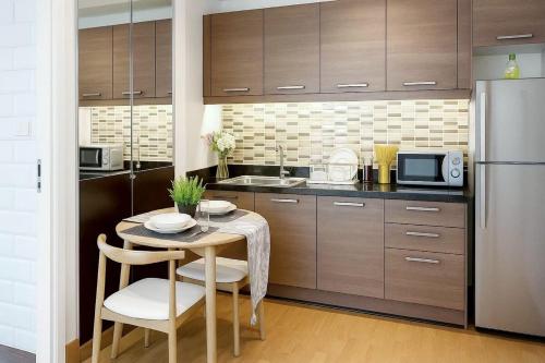 a kitchen with a small table and a refrigerator at Cozy, Spacious 2-Bedder with City, Park View, Near Nana BTS in Bangkok