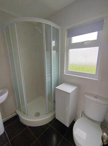 ein Badezimmer mit Dusche und Toilette und einem Fenster in der Unterkunft Antonia's Place 337 California Sands in Scratby