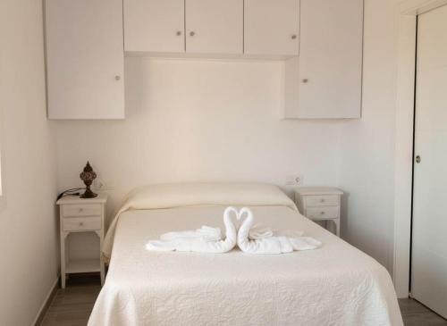 een wit bed met 2 zwanenhanddoeken erop bij Estudio cerca de la playa y del centro de conil in Conil de la Frontera
