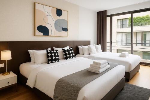 two beds in a room with two windows at Cozy, Spacious 2-Bedder with City, Park View, Near Nana BTS in Bangkok
