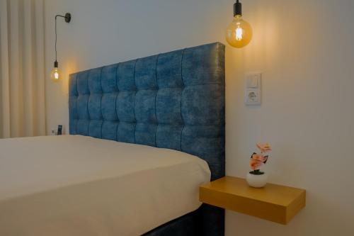 a bedroom with a white bed and a blue padded headboard at Coração de Viana AL in Viana do Castelo
