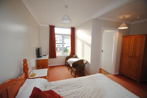 a bedroom with a bed and a desk and a window at The Curraghmore in Shanklin