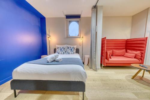 een slaapkamer met een bed en een rode bank bij La porte de Mars - Air conditioning in Reims