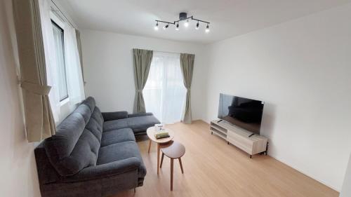 Una sala de estar con un sofá y un televisor. en 福の荘 空港3号棟, en Wada