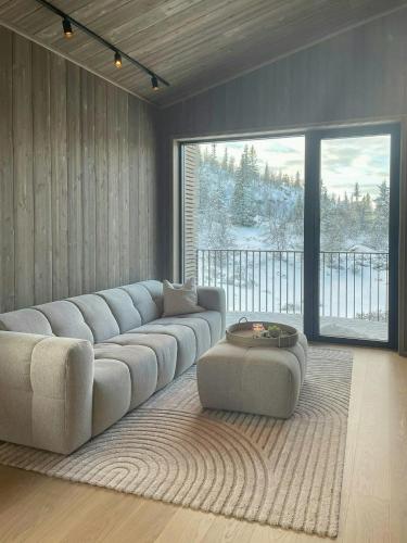 a living room with a large couch and a large window at Architect Designed Mountain Cabin At Kvitfjell in Favang