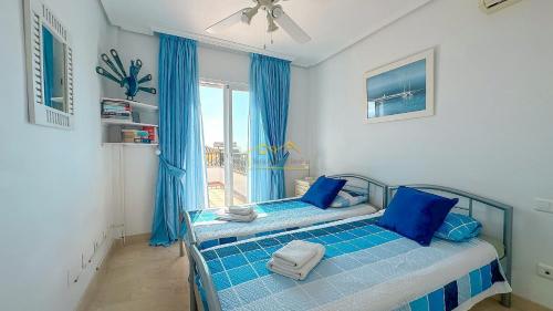 una camera da letto con un letto con lenzuola blu e una finestra di Balcón del Mar a Nerja
