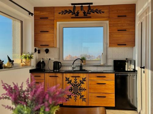 Domek na Wielkiej Górze في Waksmund: مطبخ مع دواليب خشبية ونافذة