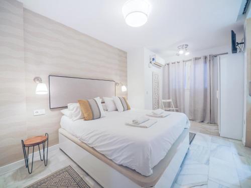 ein weißes Schlafzimmer mit einem großen weißen Bett in einem Zimmer in der Unterkunft Livemálaga Reding Beach in Málaga