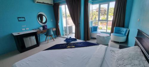 The Bedroom Kata Beach Phuket في شاطئ كاتا: غرفة نوم زرقاء مع سرير ومكتب وكراسي