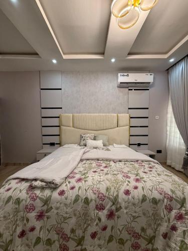 a bedroom with a large bed with a floral bedspread at Quantum Havens Apartment - Amsterdam in Akure