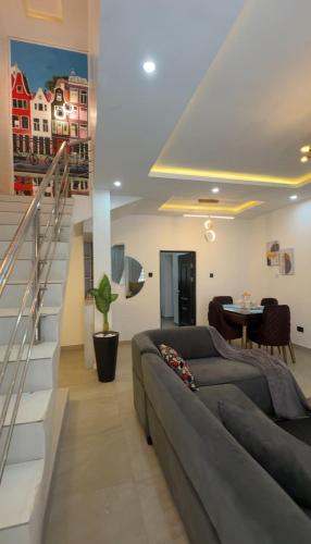 a living room with a couch and a staircase at Quantum Havens Apartment - Amsterdam in Akure
