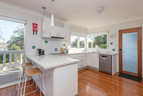 a kitchen with white appliances and a large window at Classic Meets Contemporary 1960's Beach House in Malua Bay