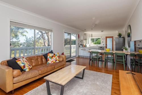 a living room with a couch and a table at Classic Meets Contemporary 1960's Beach House in Malua Bay