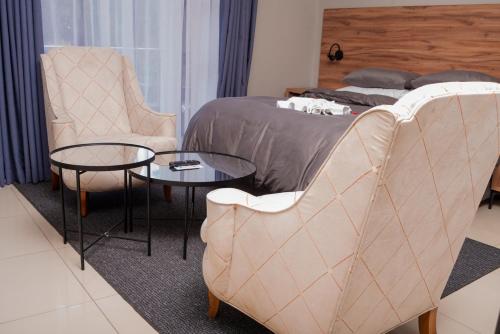 约翰内斯堡Sandown Suites and Conference Centre的一间卧室，里面有一张床、两把椅子和一张桌子