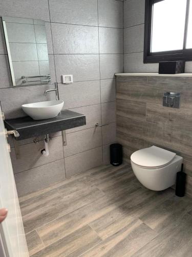 a bathroom with a white toilet and a sink at צמרת נופש in Rewaya