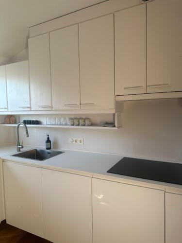 a white kitchen with a sink and white cabinets at Casa MÓRE in Niederalm