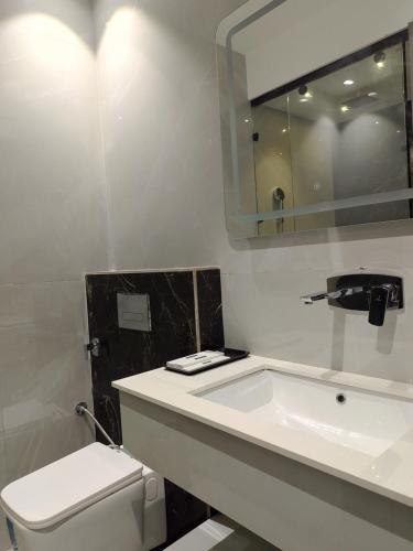 a bathroom with a sink and a toilet and a mirror at JBM resort & hotel in Jāmb
