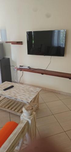 ein Wohnzimmer mit einem großen TV an der Wand in der Unterkunft Orange apartments in Watamu