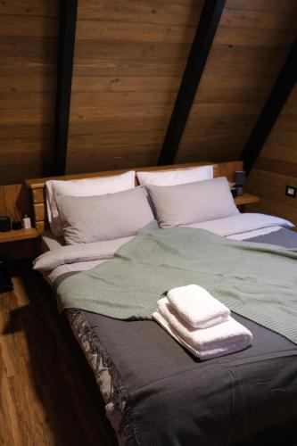 a bed with a green blanket and white pillows at Là Guesthouses in ‘Aynţūrah