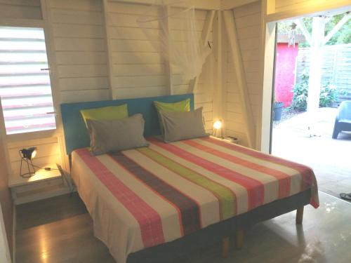 a bedroom with a bed with a striped blanket at Lukila Bungalow chez Rustine et Pompette in Saint-François