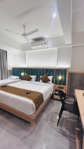 a bedroom with a large bed and a desk at Hotel Signature in Thane