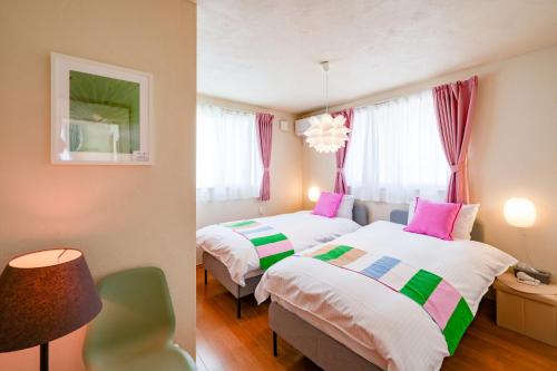two beds in a room with pink and green at Peaceful Garden Home in Ota, Entire 3BR Parking in Ota