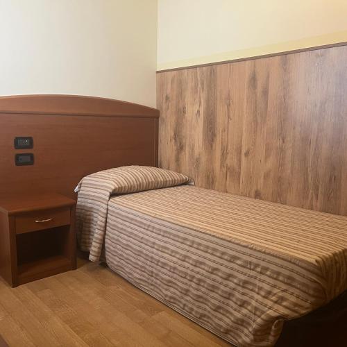 a bedroom with a bed and a wooden headboard at Hotel Ristorante Wada in Malo