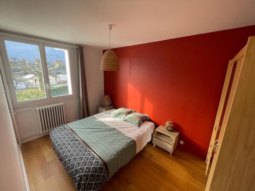 Un dormitorio con una cama con una pared roja. en Grand T2 lumineux et cosy - 1min Termes Marlioz, en Aix-les-Bains