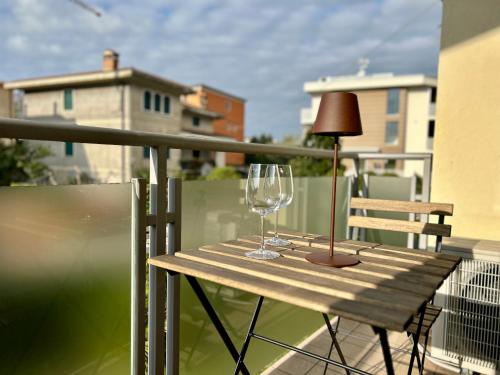 巴多利诺Grace House的阳台上的一张桌子上放着两个酒杯和一盏灯