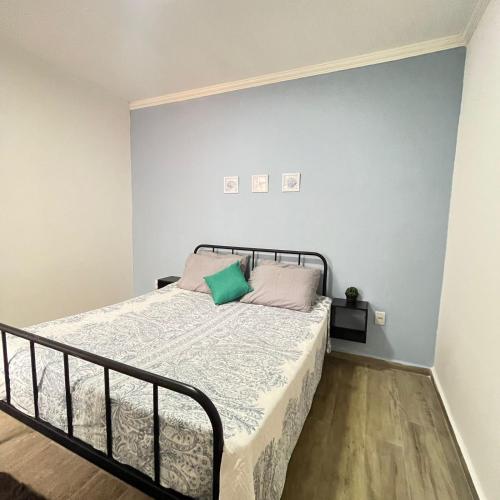 ein Schlafzimmer mit einem Bett mit einem grünen Kissen darauf in der Unterkunft Studio no Centro com ESTACIONAMENTO GRÁTIS in Poços de Caldas