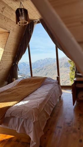 a bed in a room with a view of the mountains at GREEN GUNDAURI in K'eda