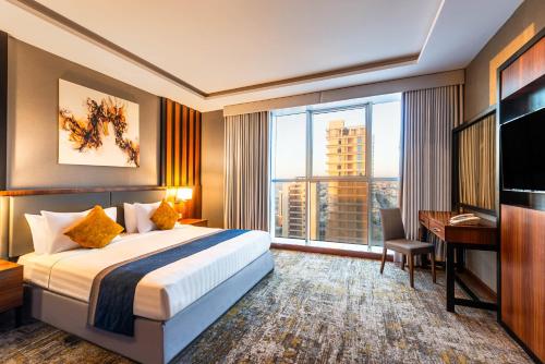a hotel room with a bed and a desk and a window at Elian Tower AlSahafa Hotel in Riyadh